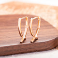 Rose gold cross shaped earrings with metallic finish and pendant design