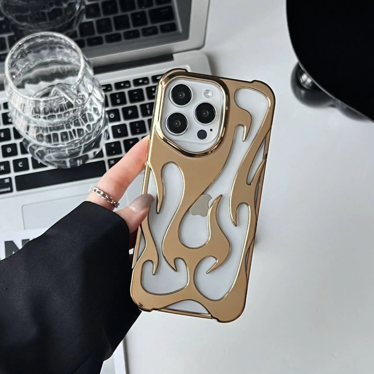 Apple iPhone case with hollow flame pattern and electroplated finish in silver, shown on a phone.