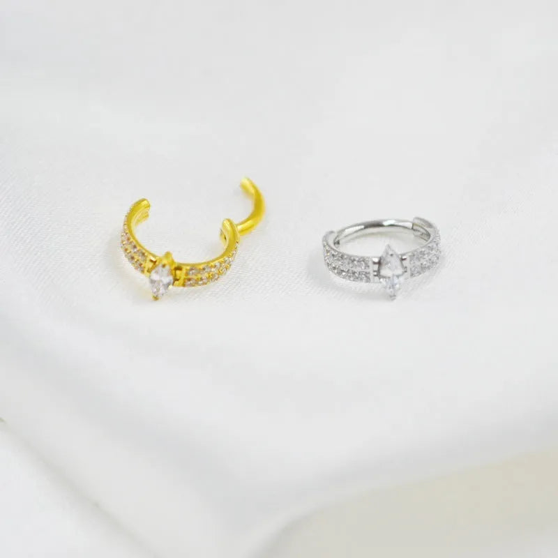Close-up of a silver heart shaped titanium steel earring with a small zircon stone.