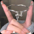 Silver adjustable bracelet with bow charm featuring bell opening detail