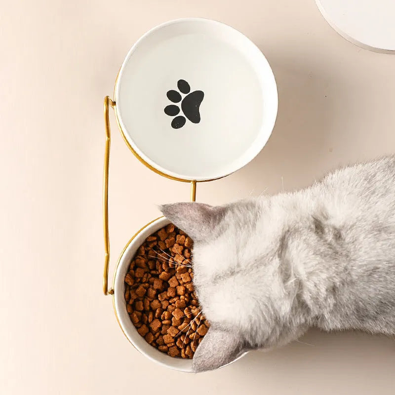 White ceramic cat food bowl with cat paw print design on black iron frame stand
