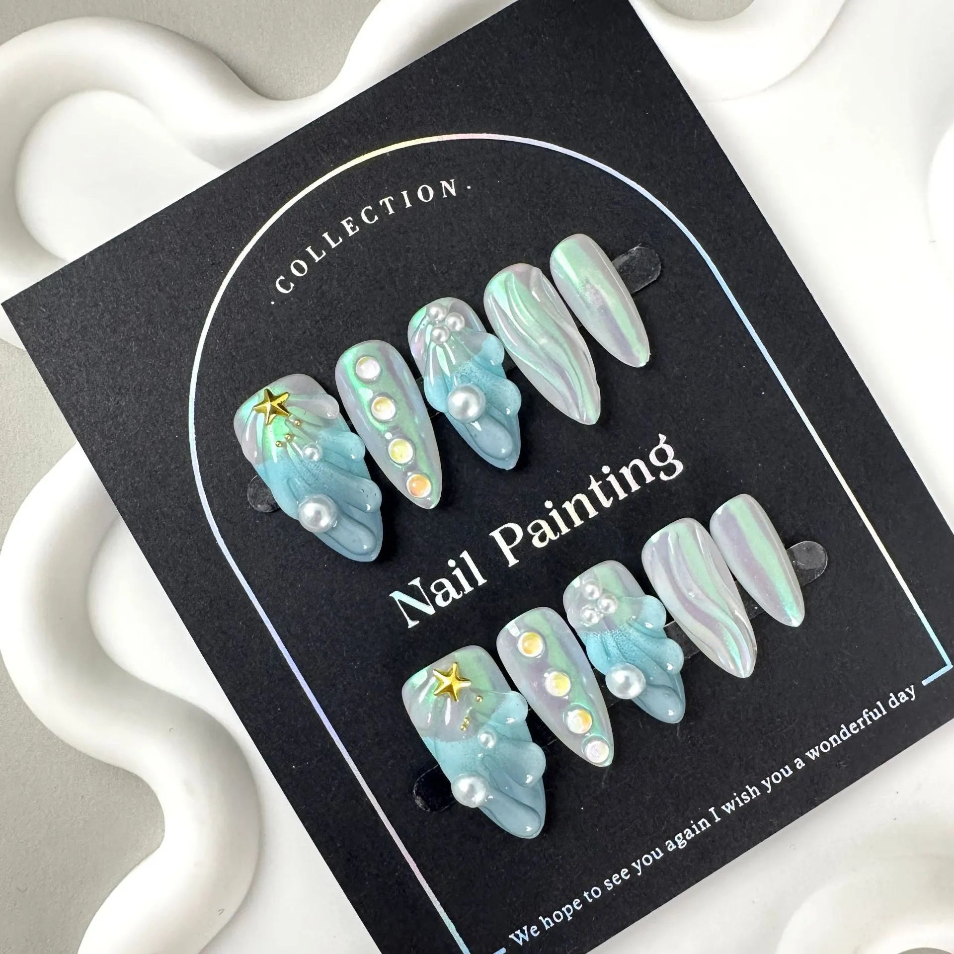 Blue plastic artificial nail tips set on a card, showing sizes labelled XS, S, M, and L.
