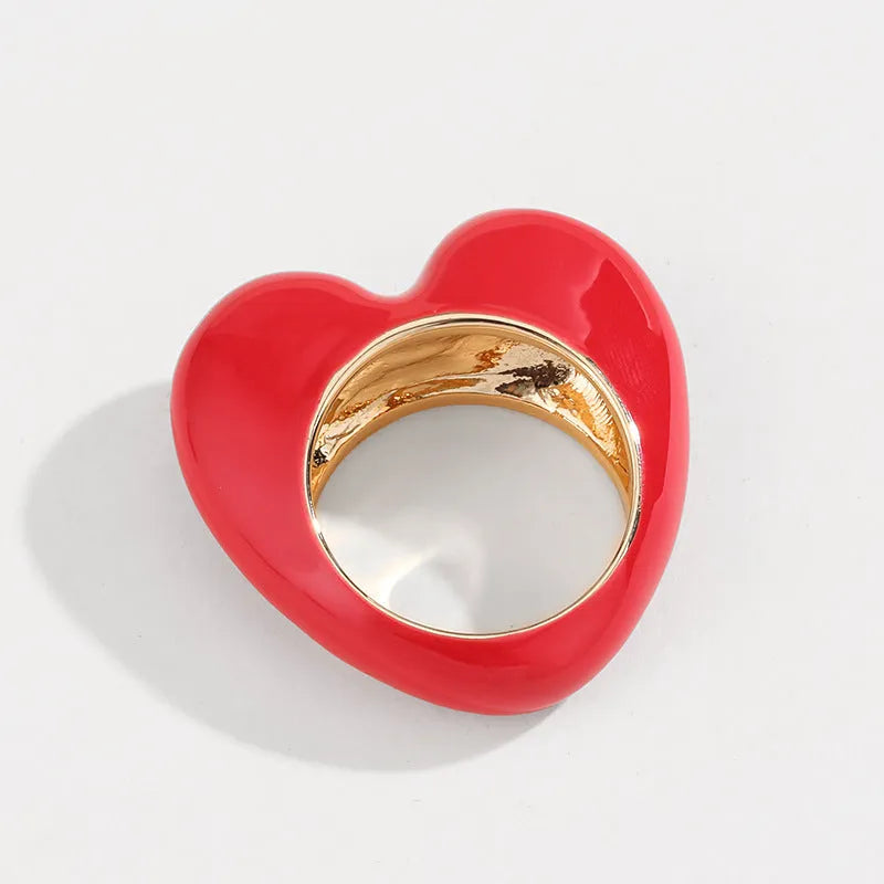 A three-dimensional heart-shaped enamel ring in zinc alloy, shown in various colours.