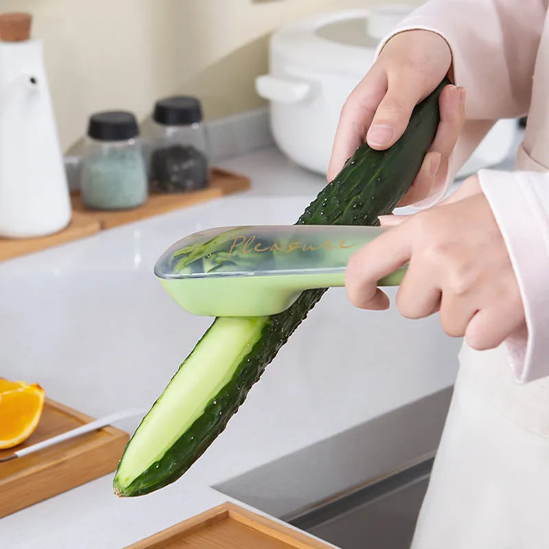 Dark green kitchen peeler with stainless steel blade inside its open storage tube on a counter.