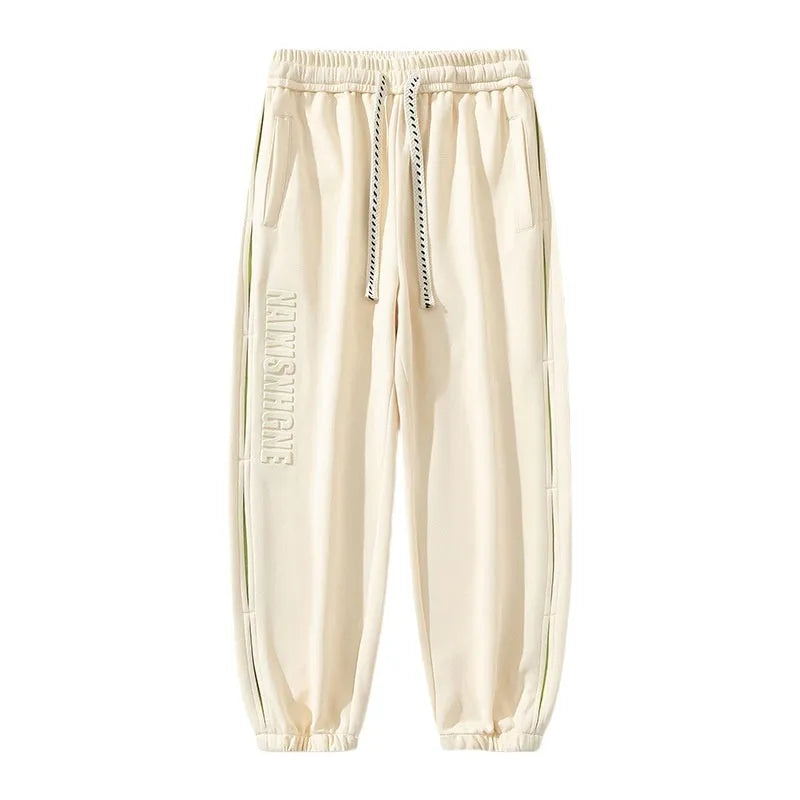 Man wearing grey green loose-fit cotton trousers with elastic ankle bands and visible stitch detailing.