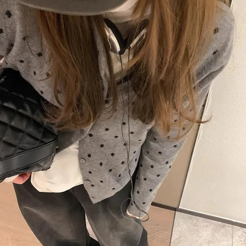 Women's grey dot knitted cardigan with long sleeves and crocheted flower detail.