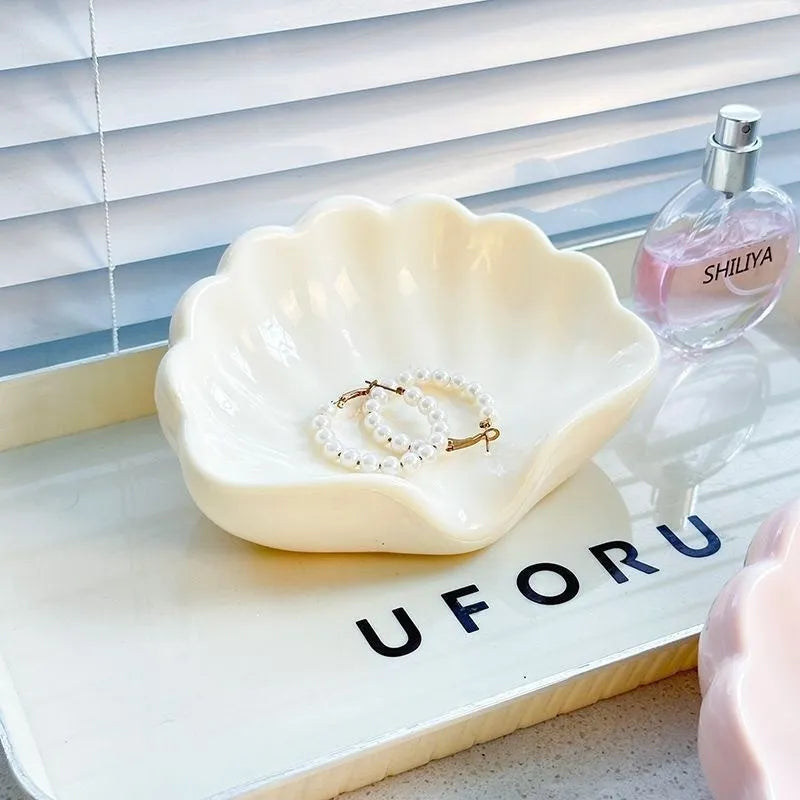 White or pink plastic shell-shaped soap dish for bathroom countertops.