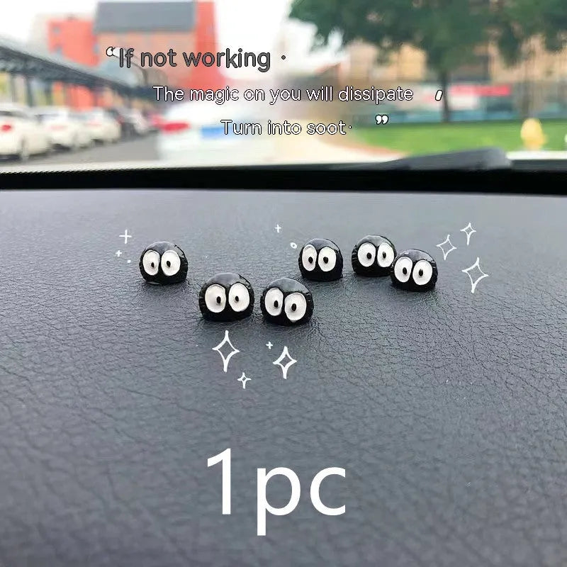 Small black cartoon-styled resin briquette car decoration ornament with traceless glue tape on a surface.