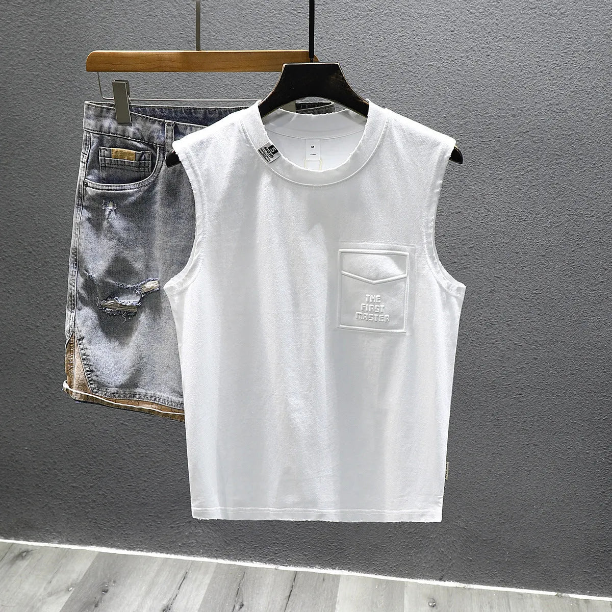 A man's solid black cotton sleeveless t-shirt with a loose fit and straight hem, laid flat.