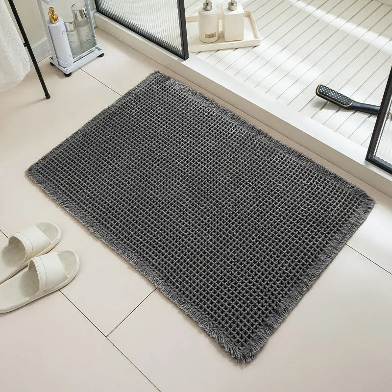 Square checkered polyester bathroom carpet on a tiled floor in a light grey colour.