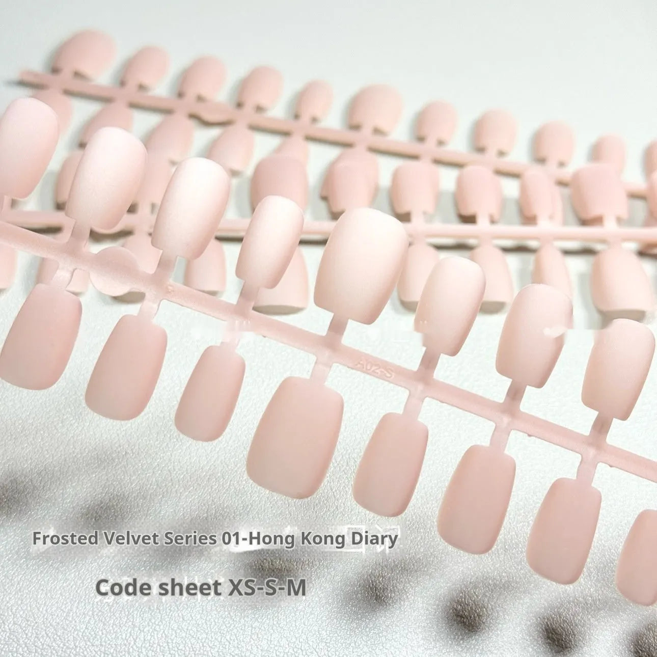 Set of frosted velvet false nails with Cat's Eye reflection in short ladder shapes on a display stand.