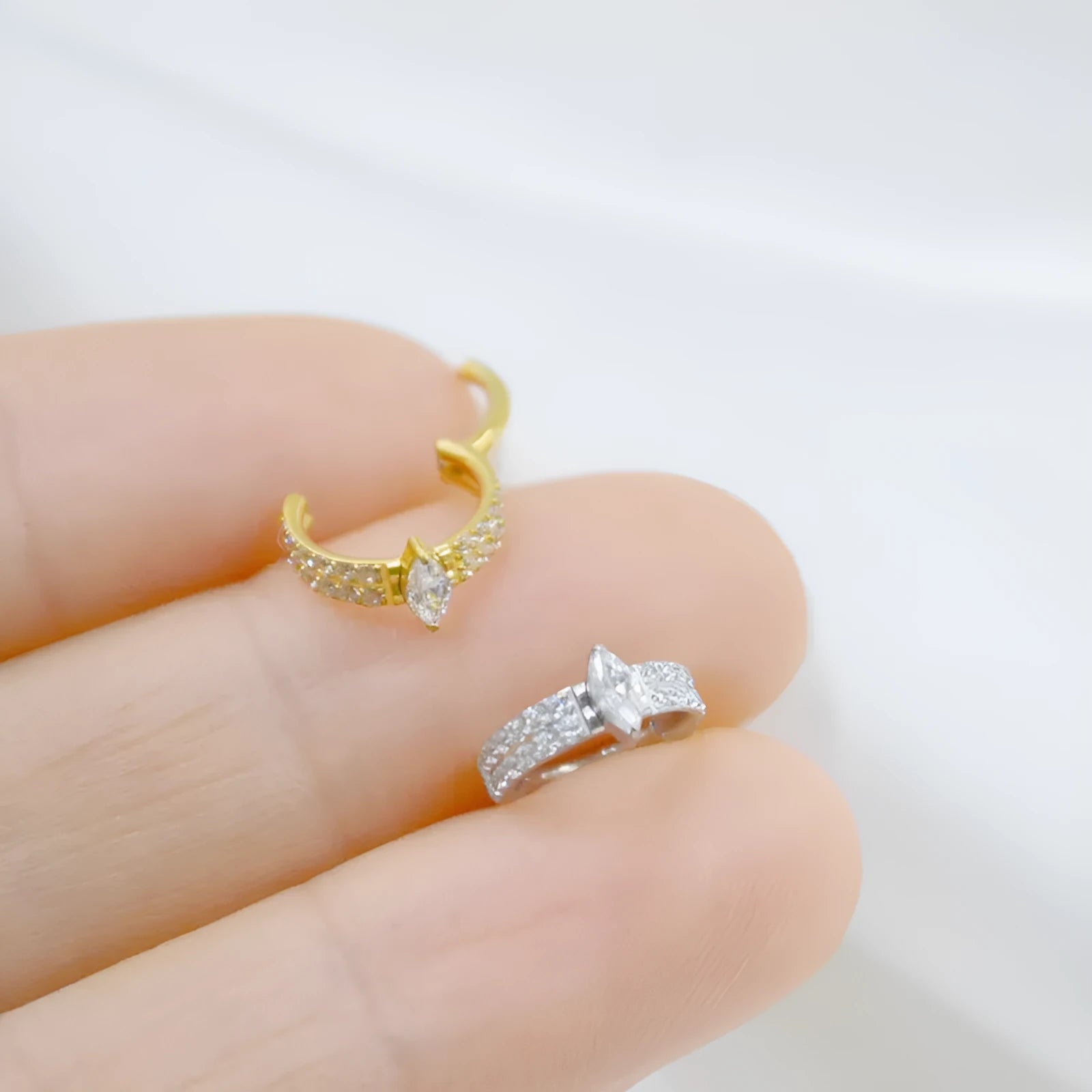 Close-up of a silver heart shaped titanium steel earring with a small zircon stone.