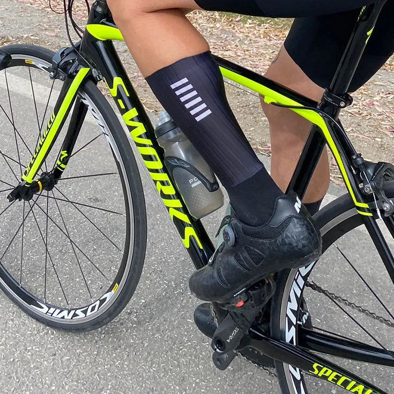 A pair of athletic cycling and running socks in a moisture-wicking fabric blend on a grey background.