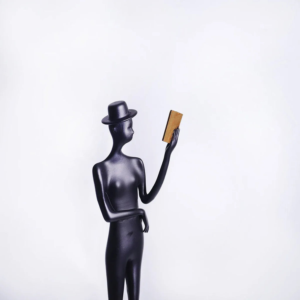 Black cast aluminium sculpture of a woman reading, modern design, 51cm tall.