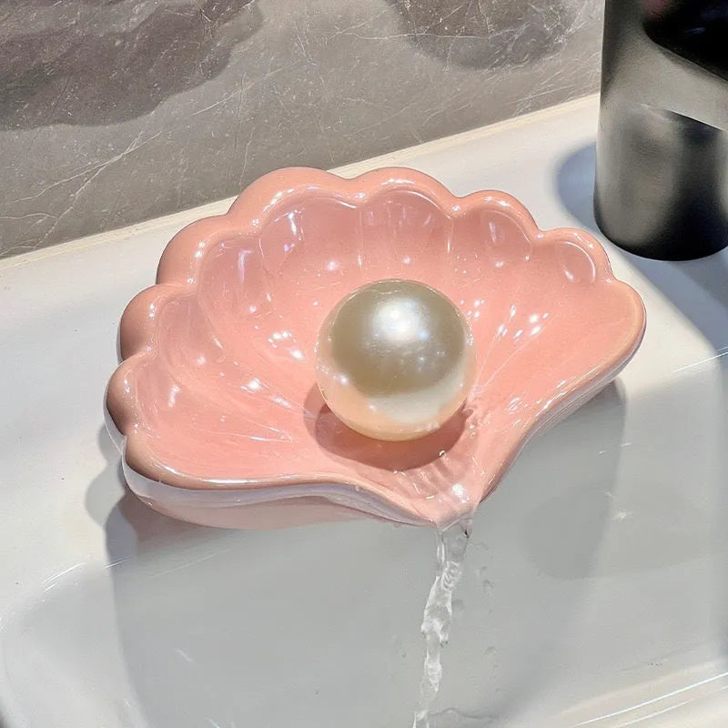 White or pink plastic shell-shaped soap dish for bathroom countertops.