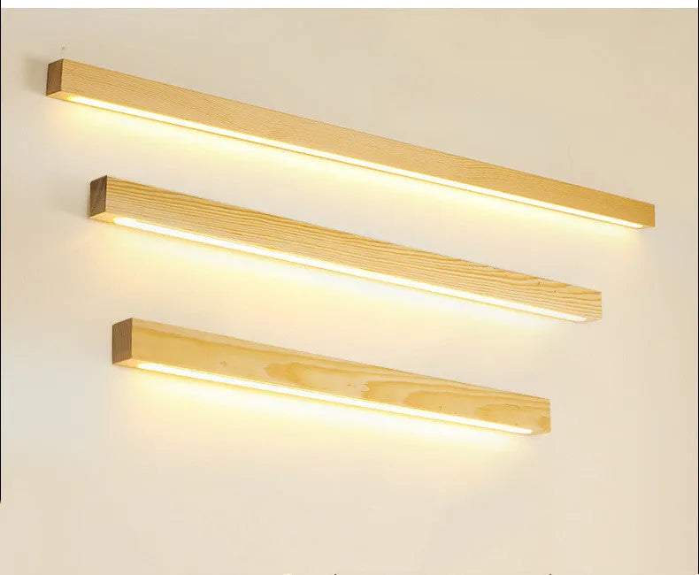 Walnut-coloured wood and acrylic minimalist LED strip wall lamp in three sizes on a white wall.