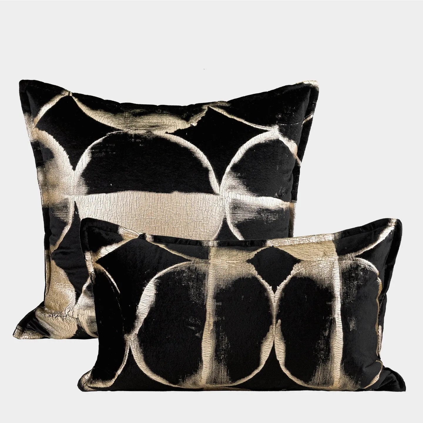 Black gold abstract patterned square decorative pillow with a soft flannel texture on a grey sofa.