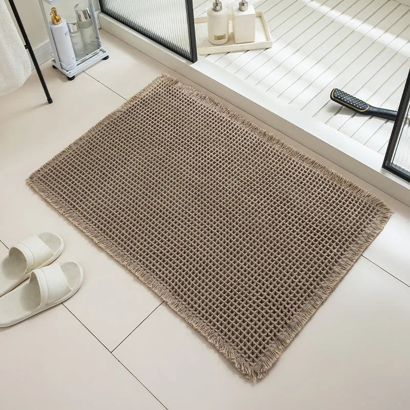Square checkered polyester bathroom carpet on a tiled floor in a light grey colour.