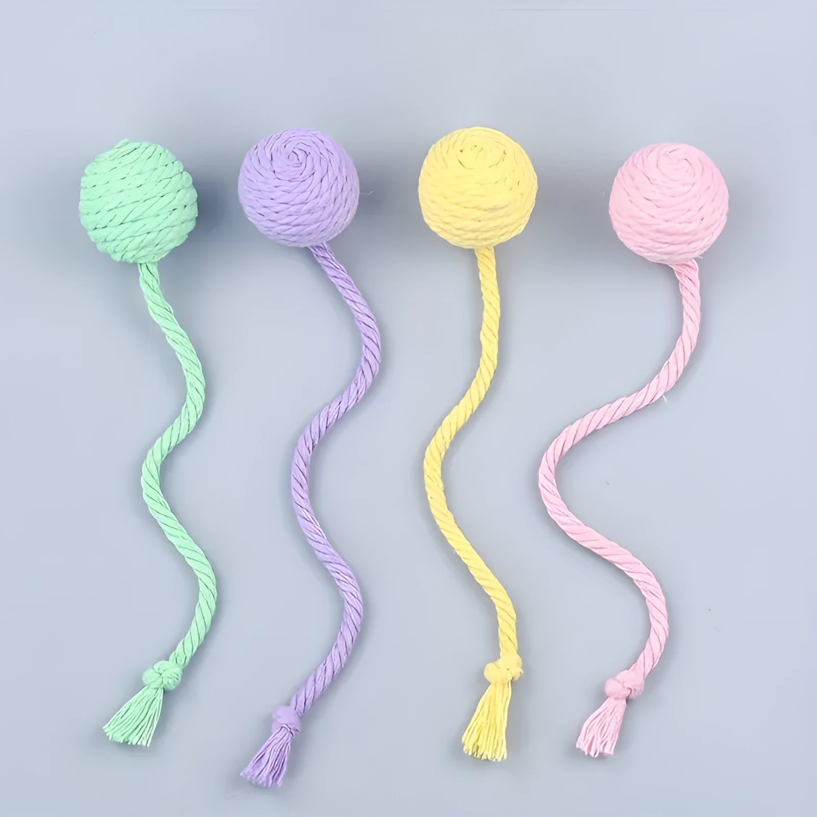 Green cat toy ball with a rope handle looped through it, shown next to a smaller pink version.