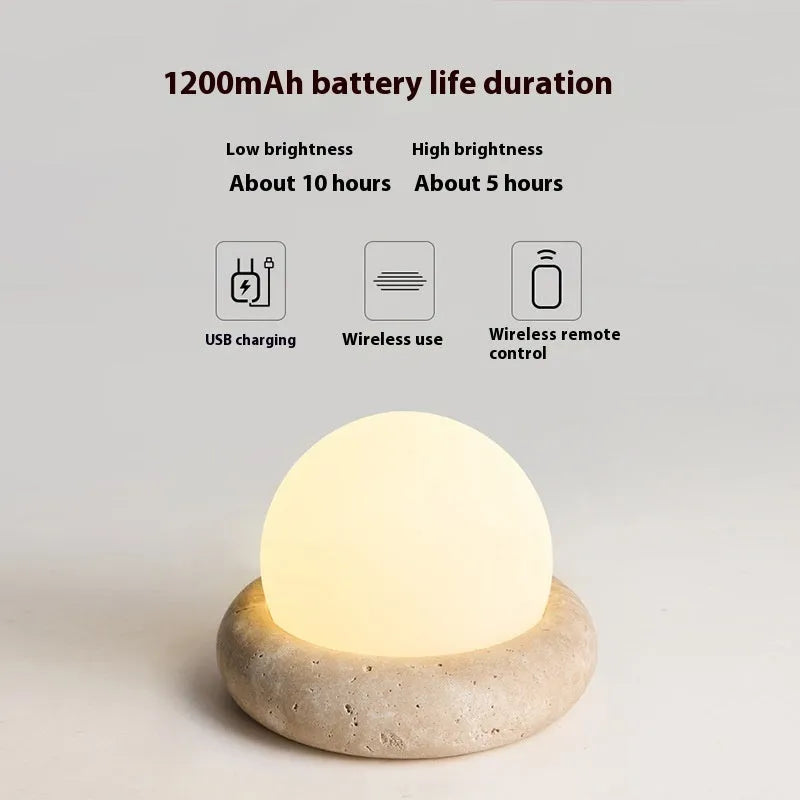 Cream-coloured round bedside night lamp with remote control on wooden table