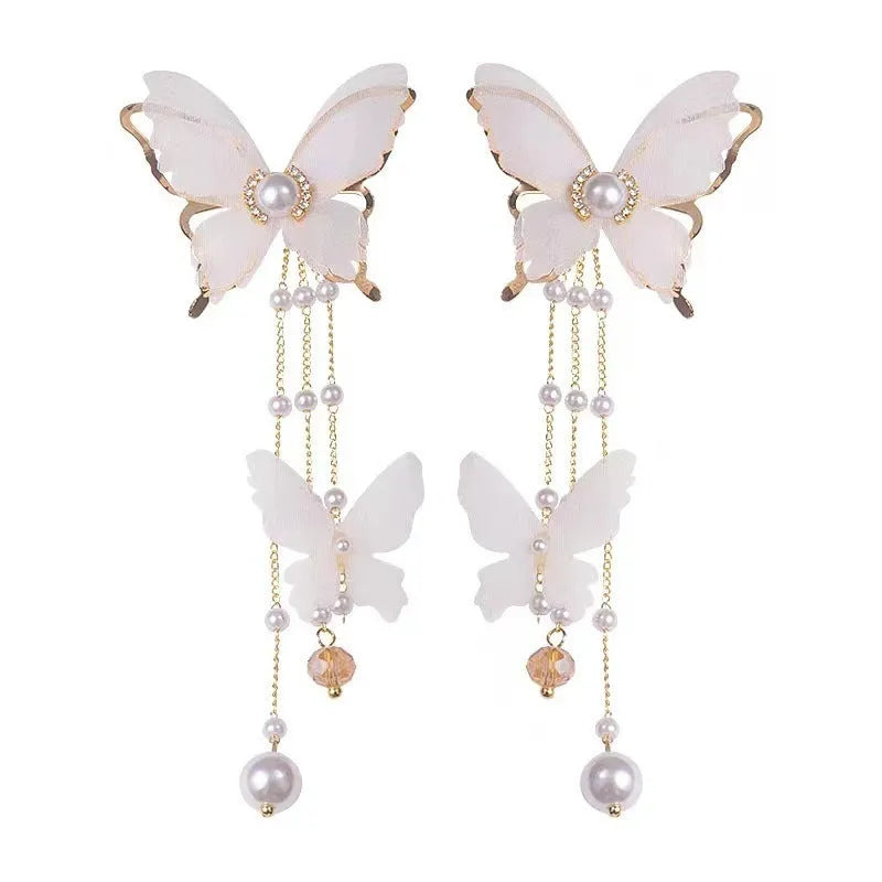 White butterfly-shaped earrings with lace detail, pearls, rhinestones, and a dangling tassel.