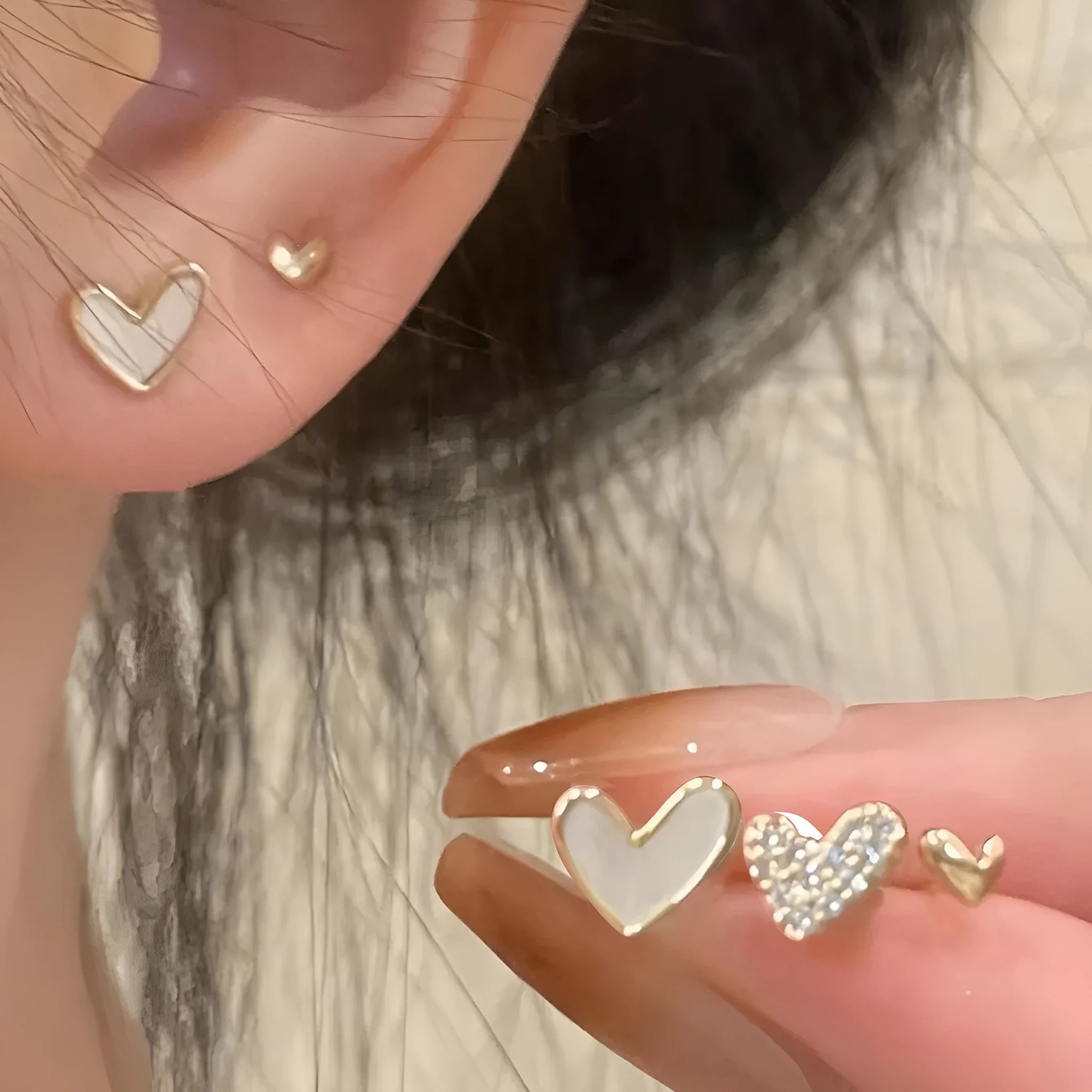 Three pairs of heart-shaped alloy earrings in gold, black, and pink with electroplated finish