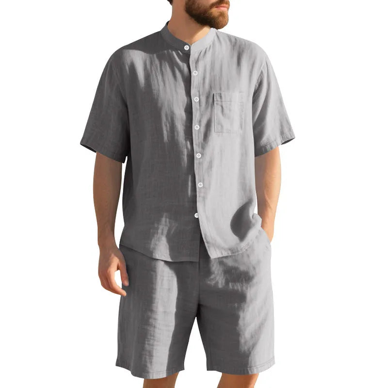 Man wearing a light blue linen blend Henry collar short sleeve suit top with matching shorts.