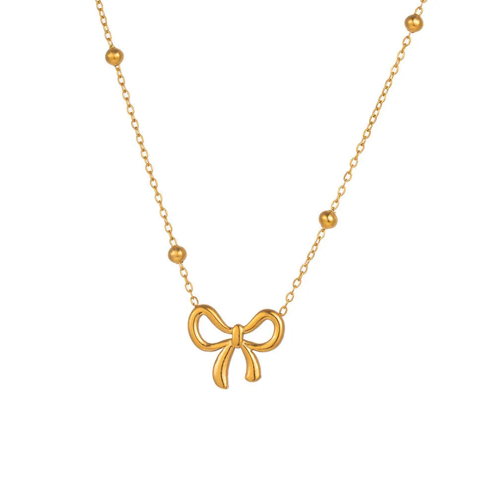 Gold coloured titanium steel necklace with a bow charm on a cross chain.