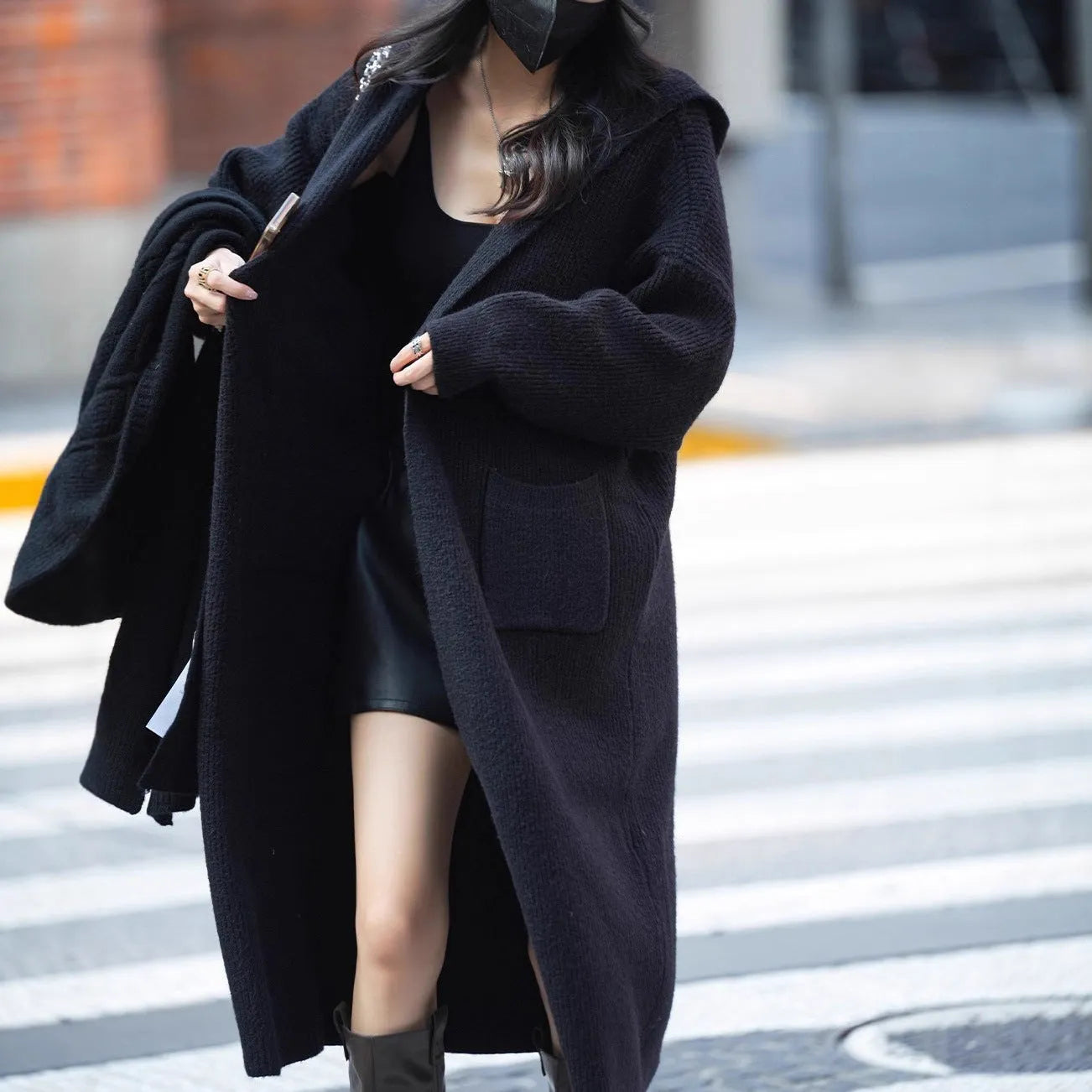 Long grey knitted women's cardigan with a hood, styled like a trench coat with long sleeves.