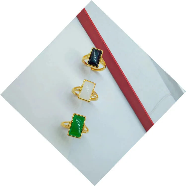 Adjustable brass gold-plated ring with a long black gemstone inlay on a finger.
