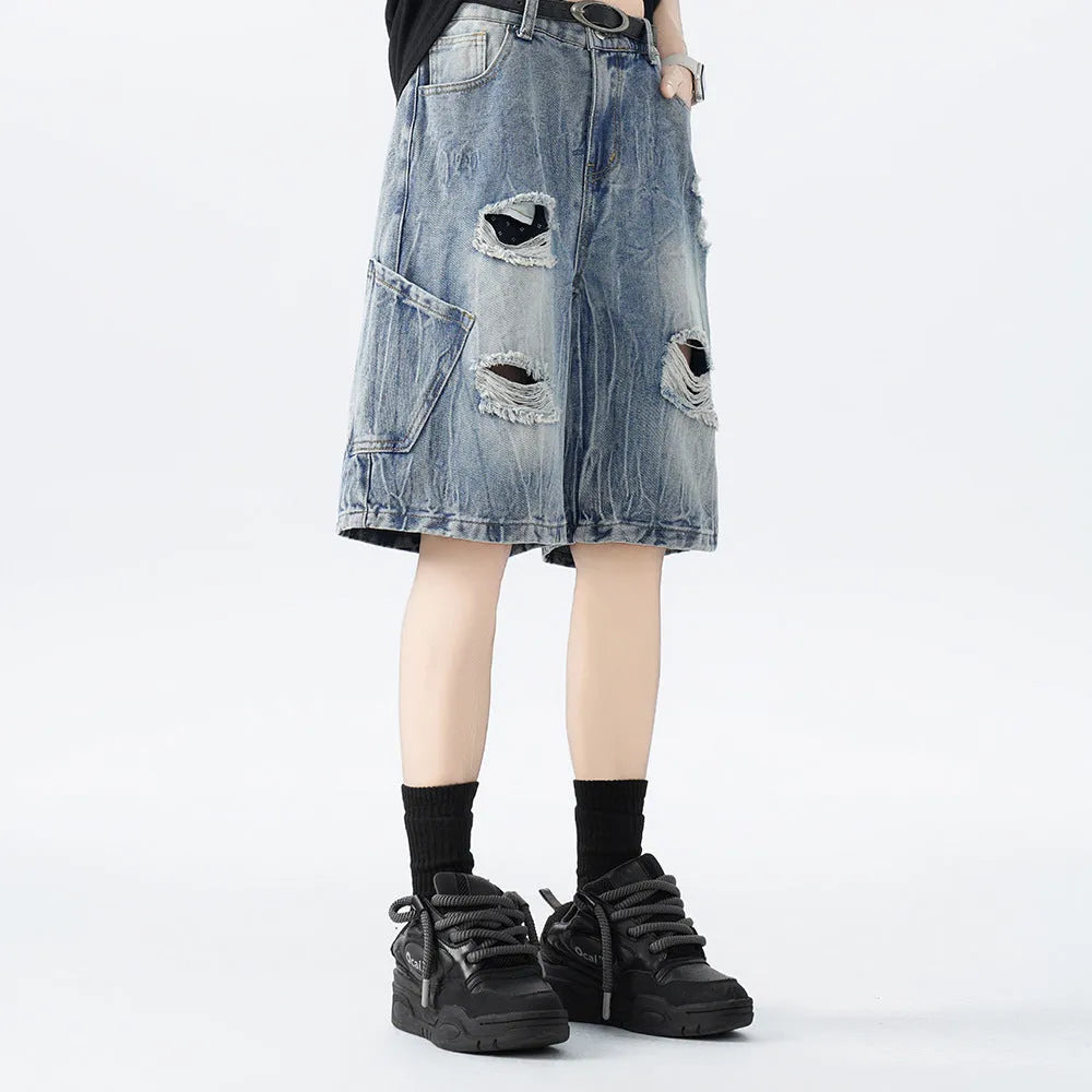 Model wearing loose-fit washed denim shorts with ripped details in blue.