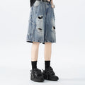 Model wearing loose-fit washed denim shorts with ripped details in blue.