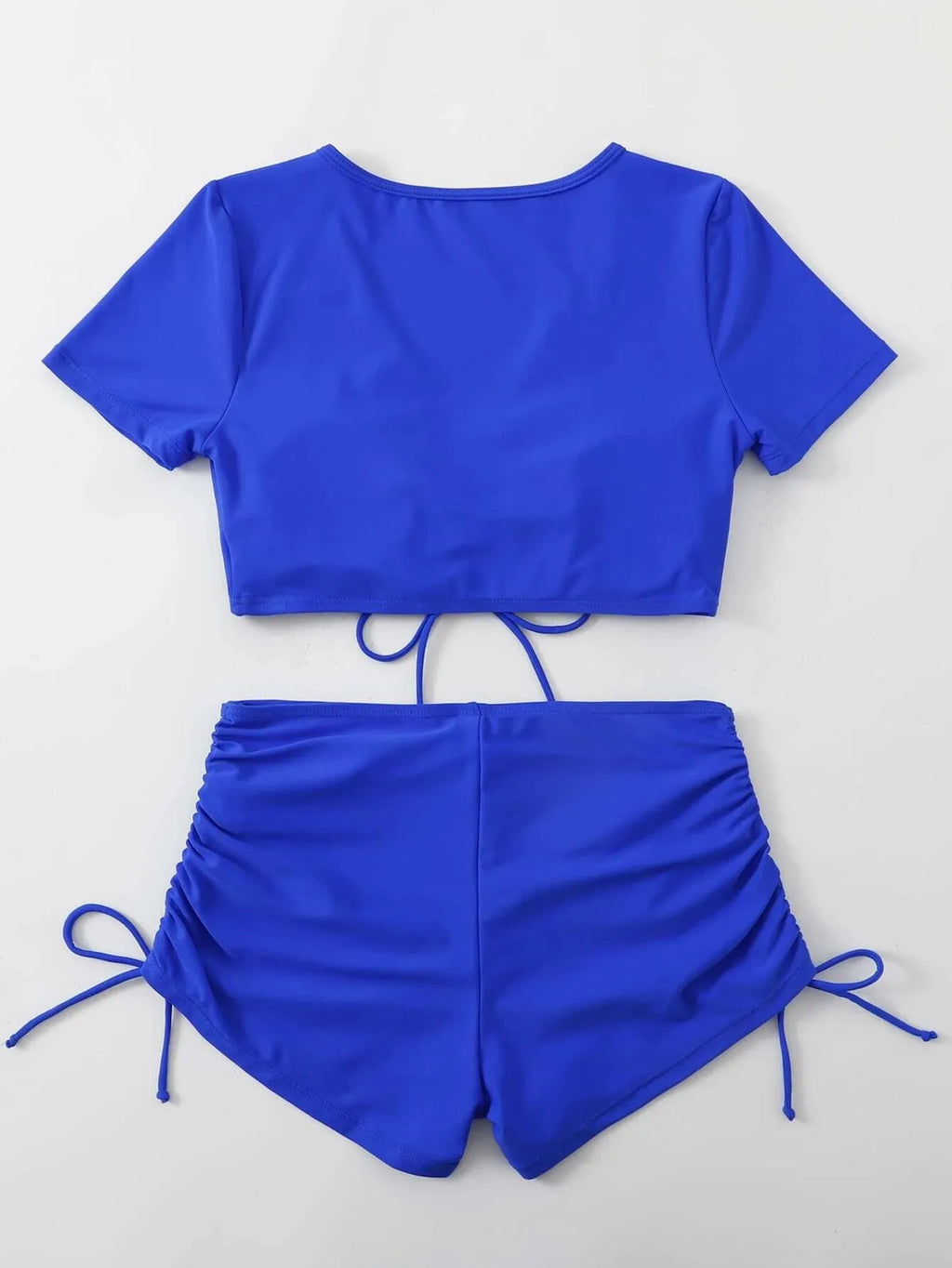 Ladies black lace-up swimsuit top with bow and matching shorts laid flat.