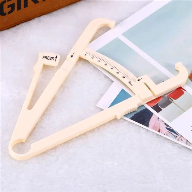 Clear acrylic body fat caliper skin fold thickness meter showing measurement scale