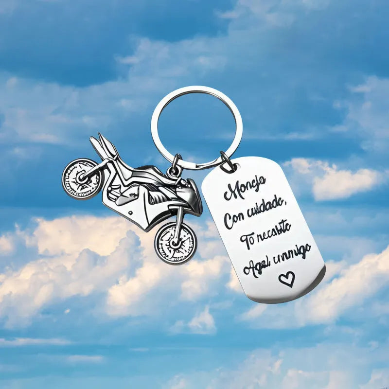 Close-up of a metal motorcycle-themed inspirational keychain next to a red flannel storage bag