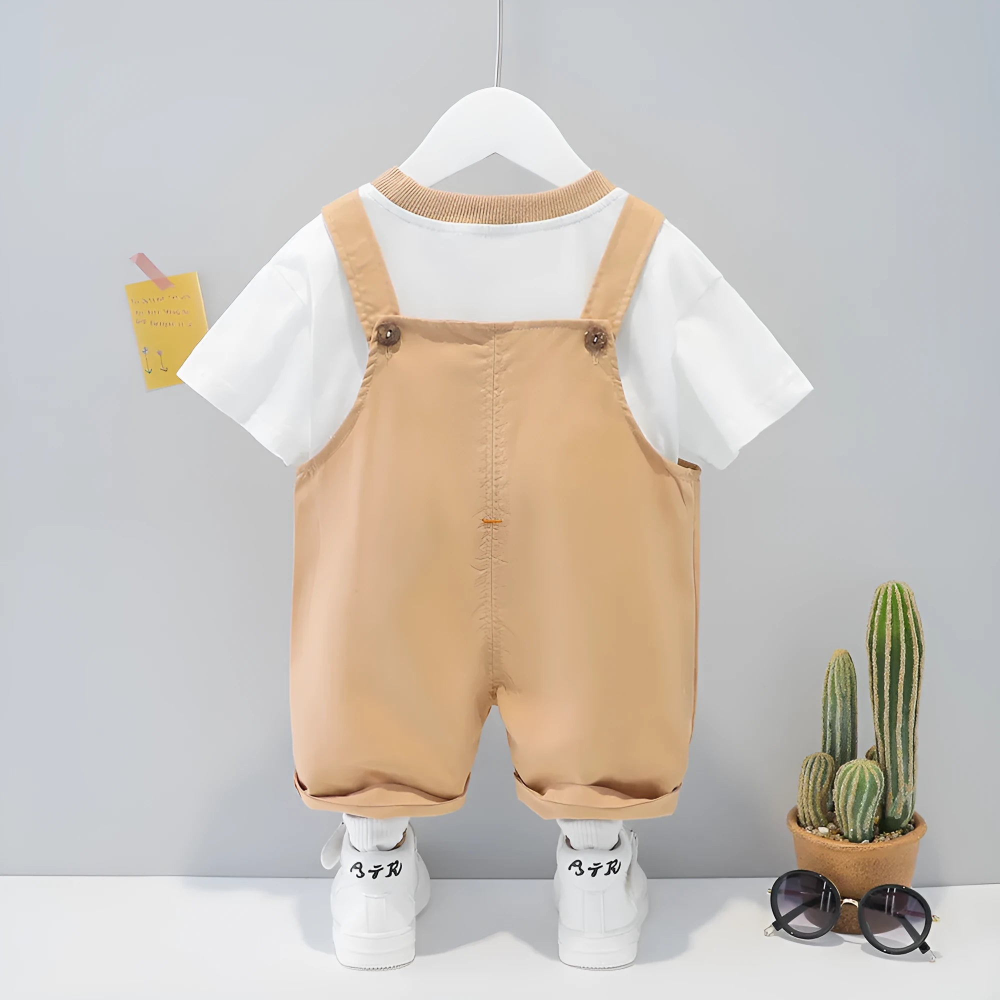 Baby wearing yellow cotton short-sleeved overalls with a cartoon print and openable straps.