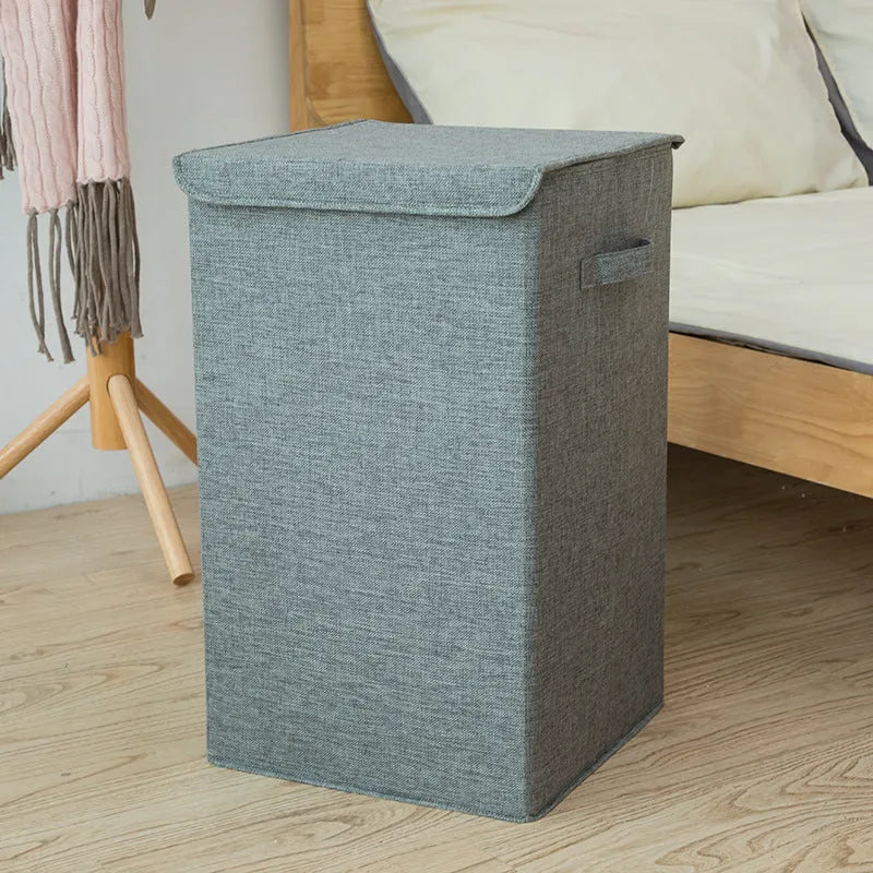 Grey foldable cotton linen storage basket shown next to a folded towel and a book.