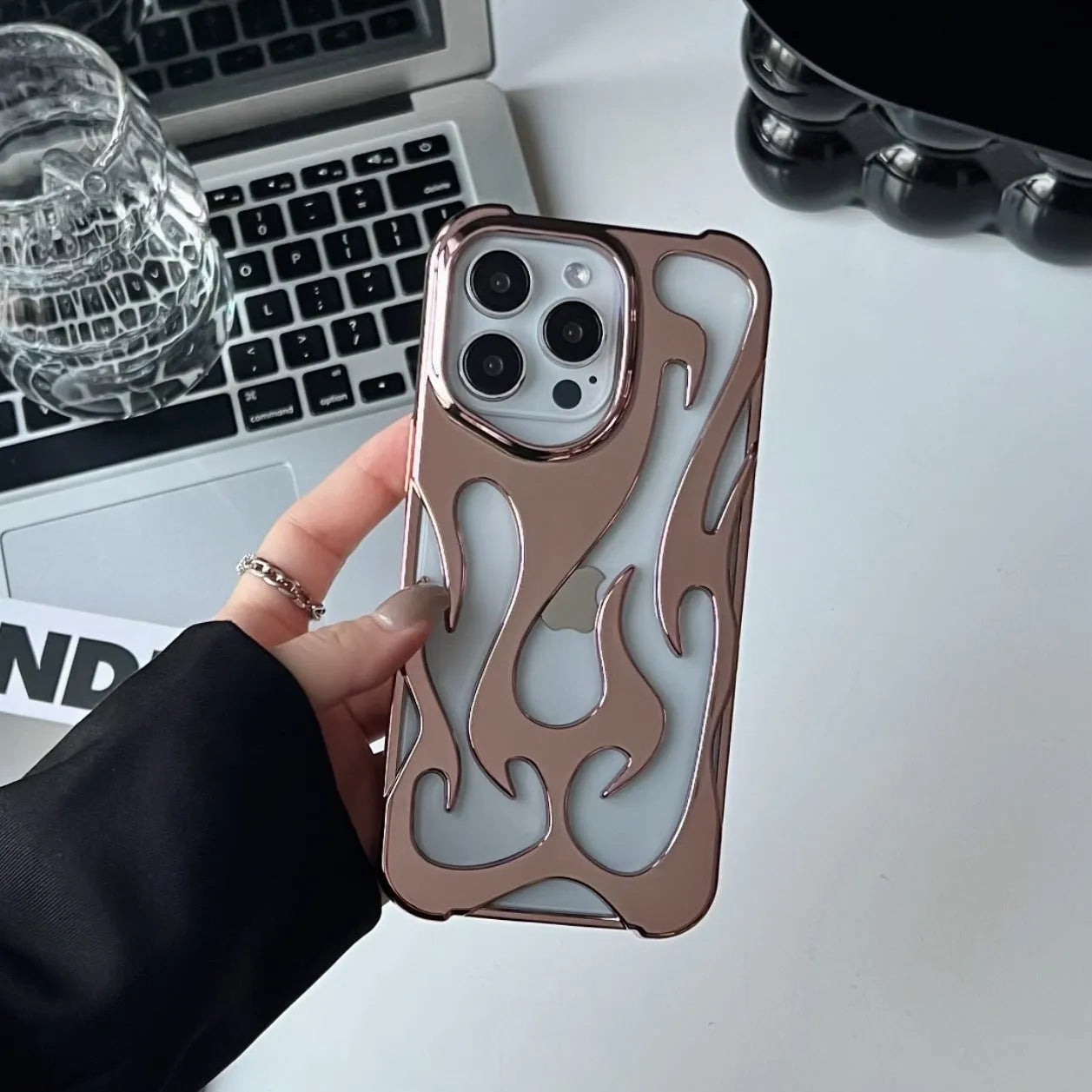 Apple iPhone case with hollow flame pattern and electroplated finish in silver, shown on a phone.