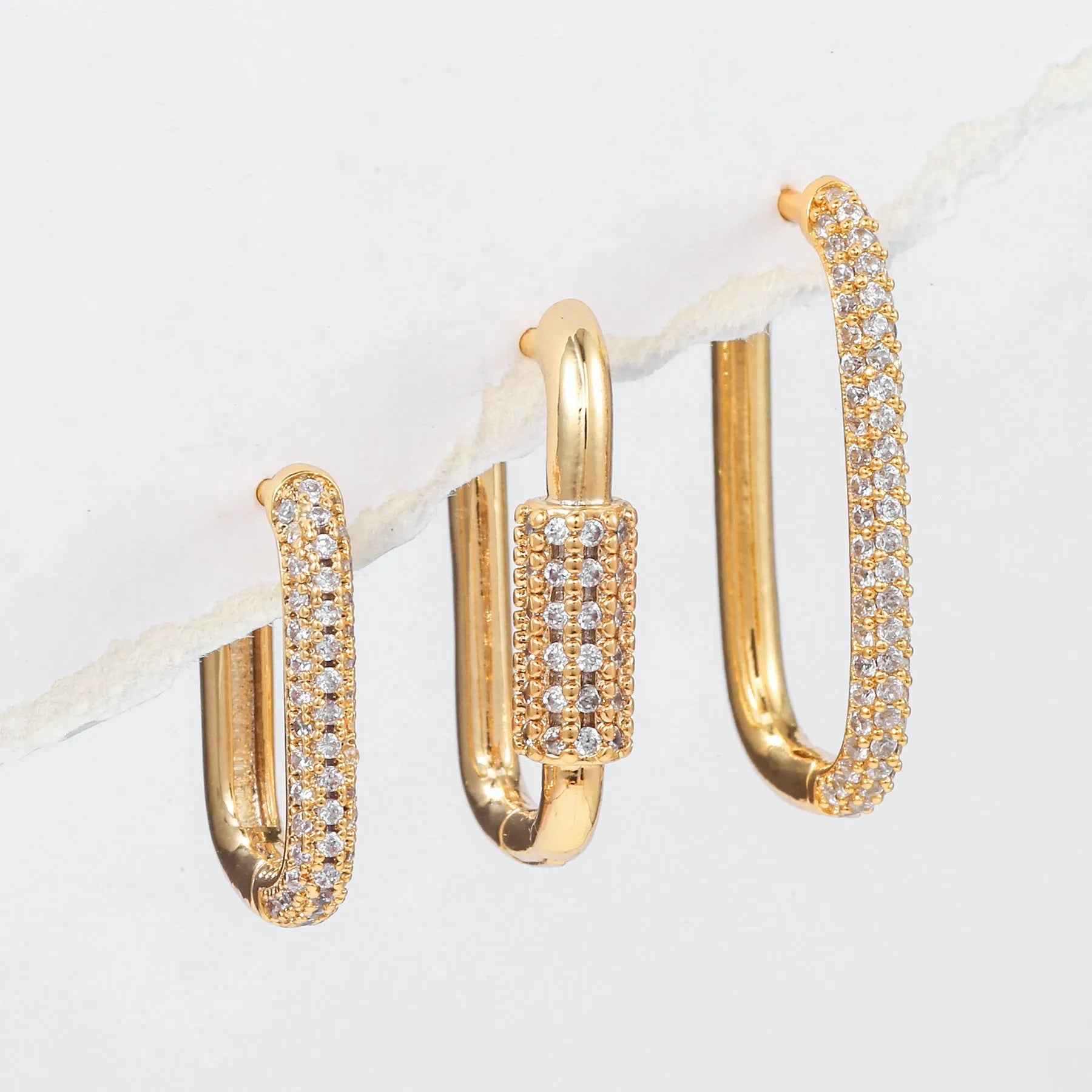 Geometric ear clips set with micro inlaid zircon detailing on copper, showing ellipse and quadrilateral shapes in gold and white finishes