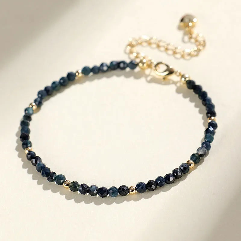 Blue tourmaline bracelet with 3mm cut beads and spacer design on white background