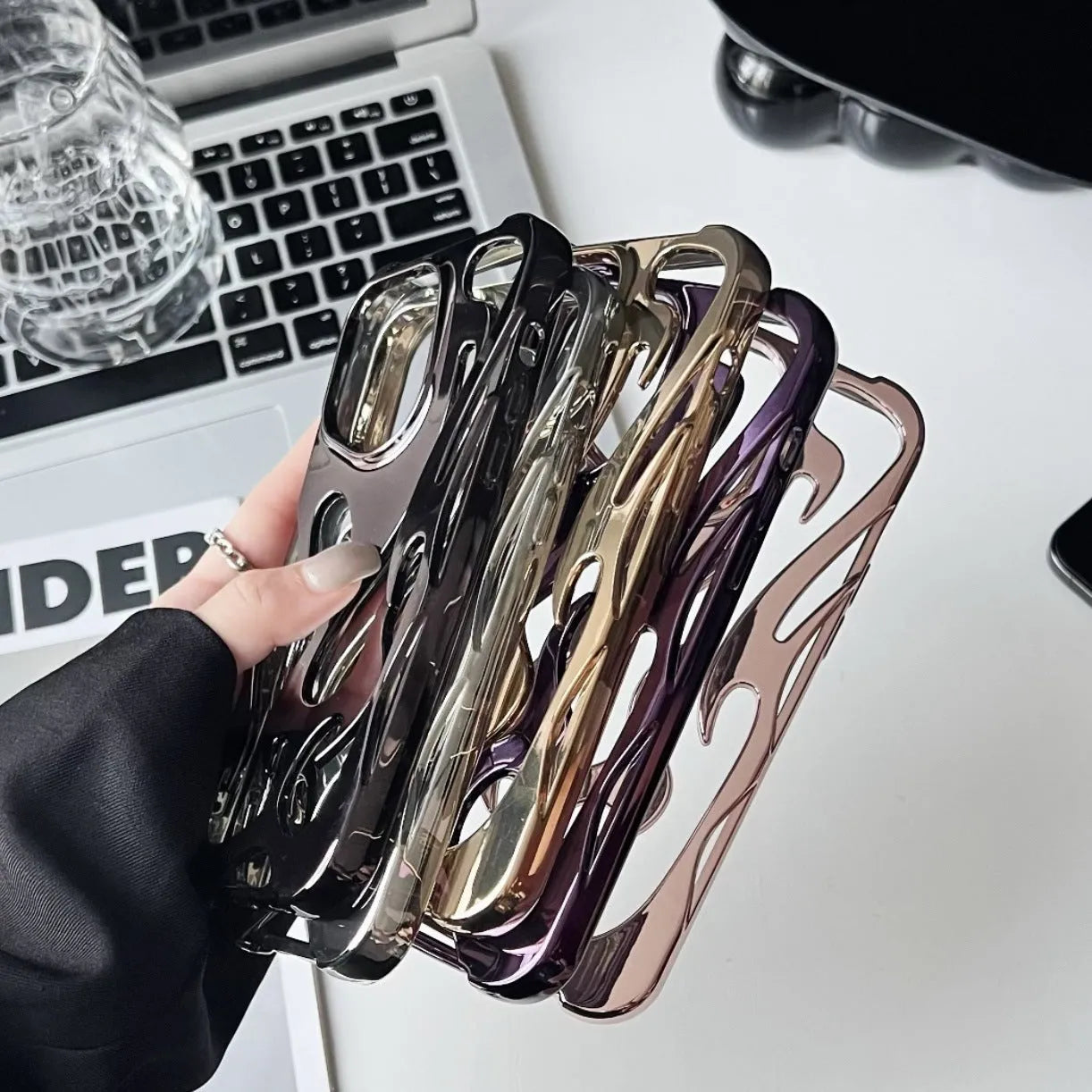Apple iPhone case with hollow flame pattern and electroplated finish in silver, shown on a phone.