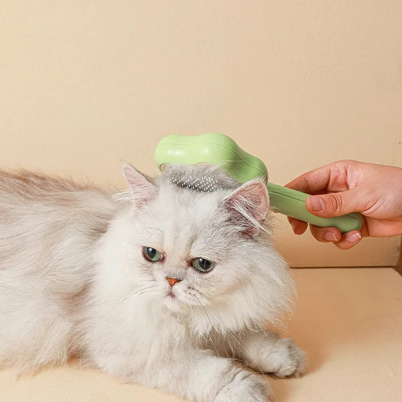 Green self-cleaning stainless steel pet comb with removable needle head on a white background.