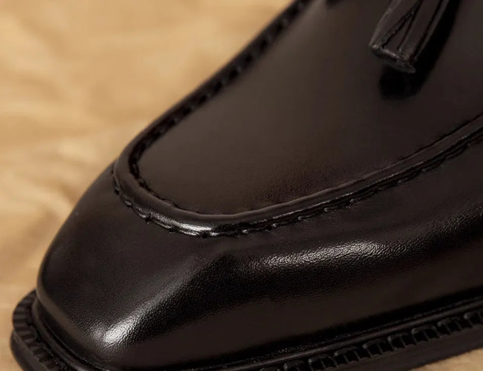 Men's black genuine leather slip-on loafers with fringed detailing on a white background