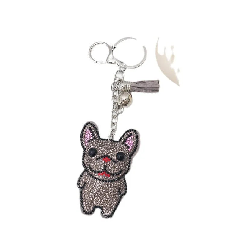 Close-up of a French dog style cartoon bear rhinestone keychain charm on a keyring.