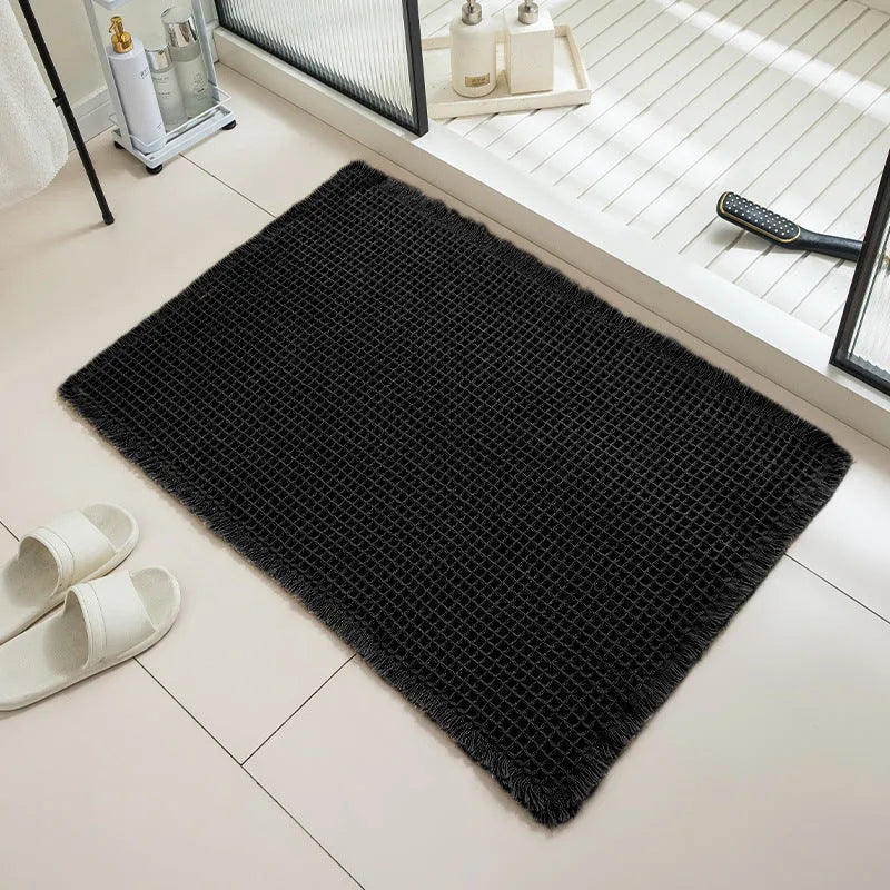 Square checkered polyester bathroom carpet on a tiled floor in a light grey colour.