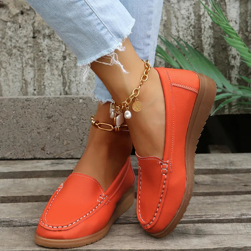 Women's flat slip-on loafers in PU leather, showing colour options and round toe design with decorative stitching.