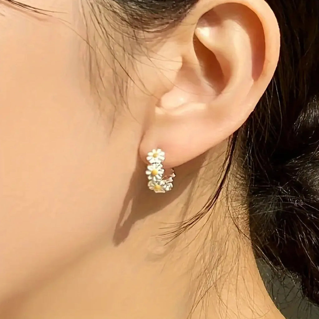 Pair of white daisy flower-shaped ring earrings with a gem inlay detail.