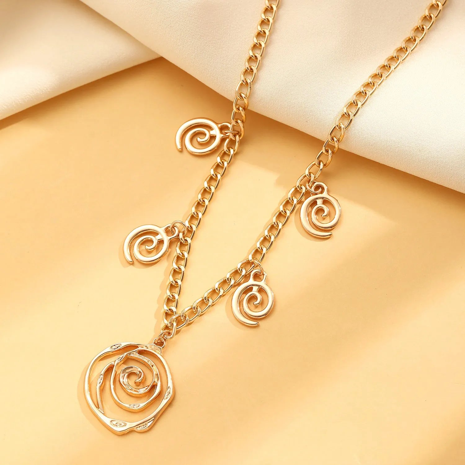 Spiral donut jewellery set showing necklace, bracelet and ear hooks in gold finish with geometric circle design
