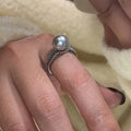 Adjustable black geometric pearl copper ring for women on a finger.