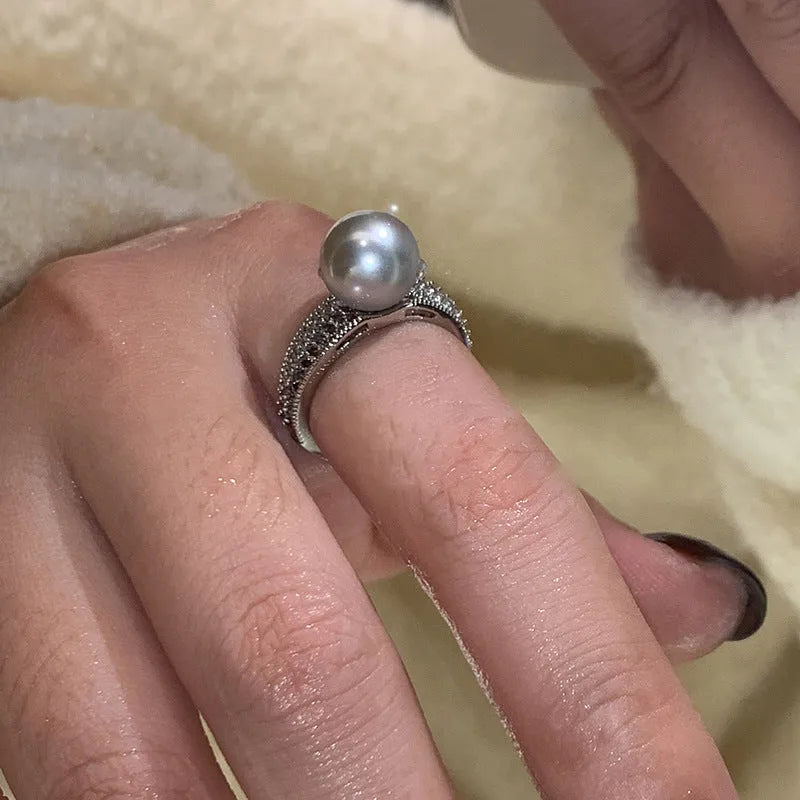 Adjustable black geometric pearl copper ring for women on a finger.